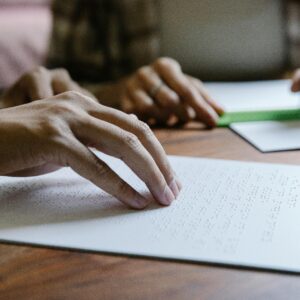 Hands feel Braille text on paper, demonstrating tactile reading and sensory education.